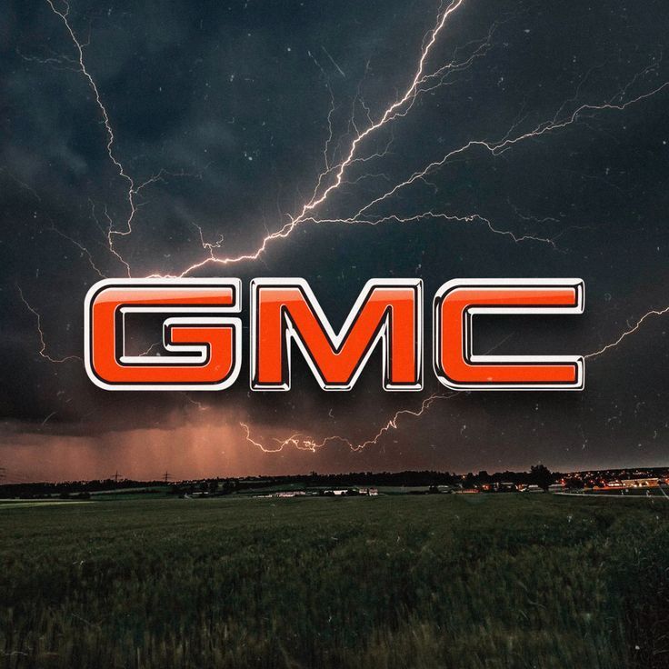 GMC logo with orange letters and chrome border over a stormy landscape with lightning.