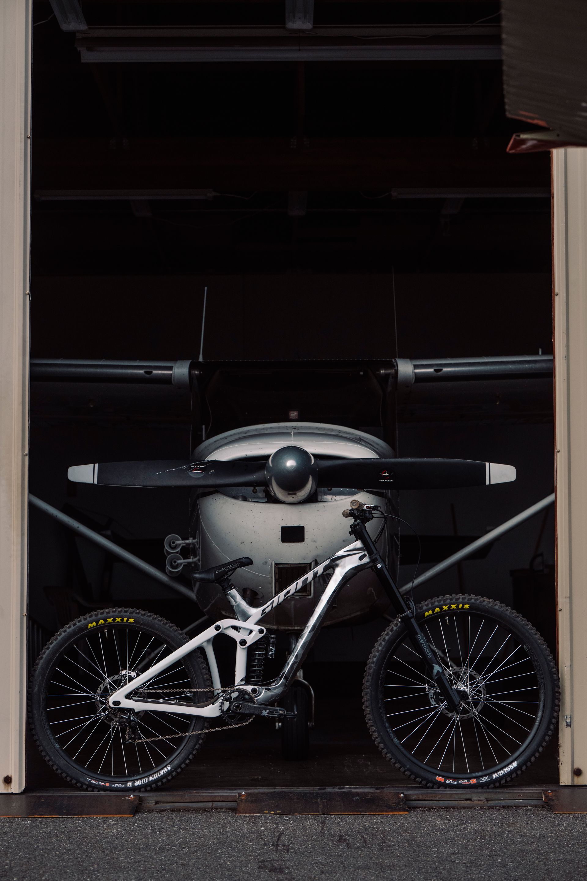 Mountain bike in front of the propeller of a small plane inside a hangar.