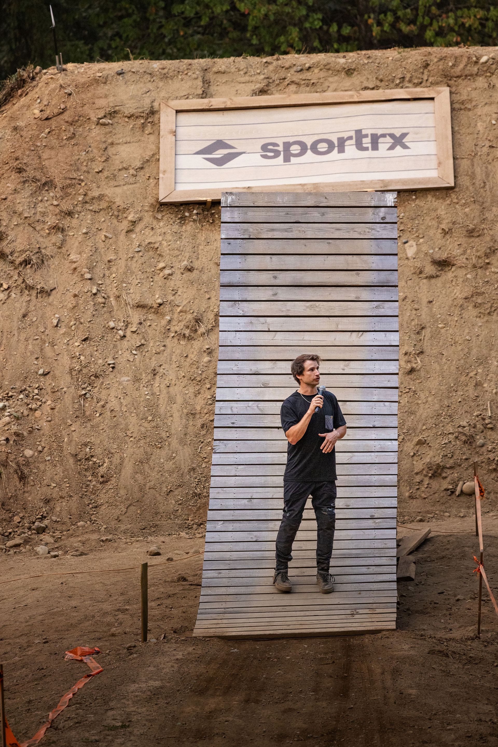 Man speaking in front of wooden ramp; 