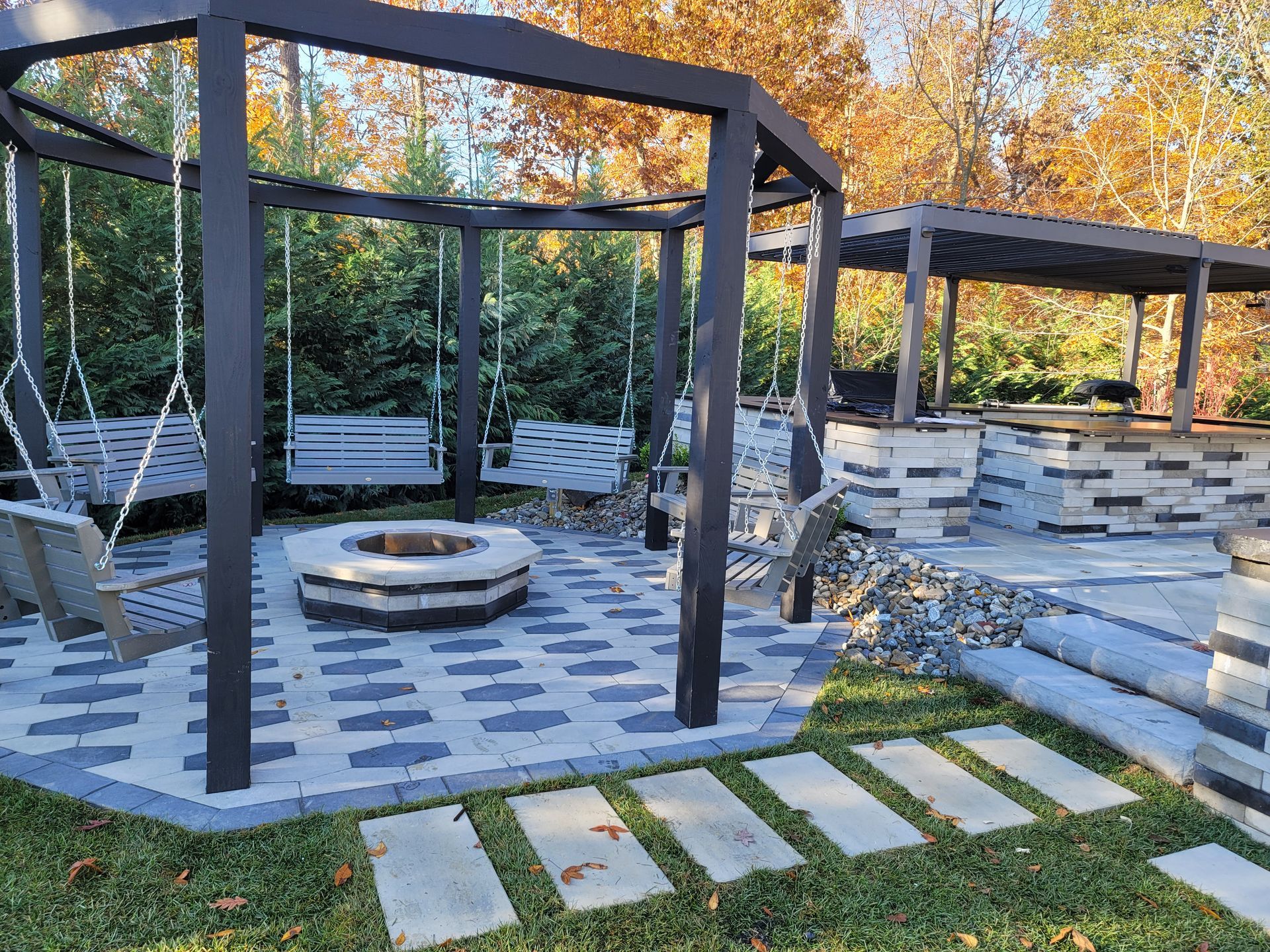Backyard patio with stone, seating, and a covered porch. Houses in background.
