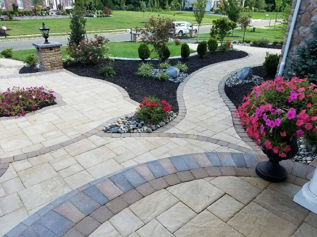 Brick paver pathways through landscaped garden beds; petunias, shrubs, and trees.