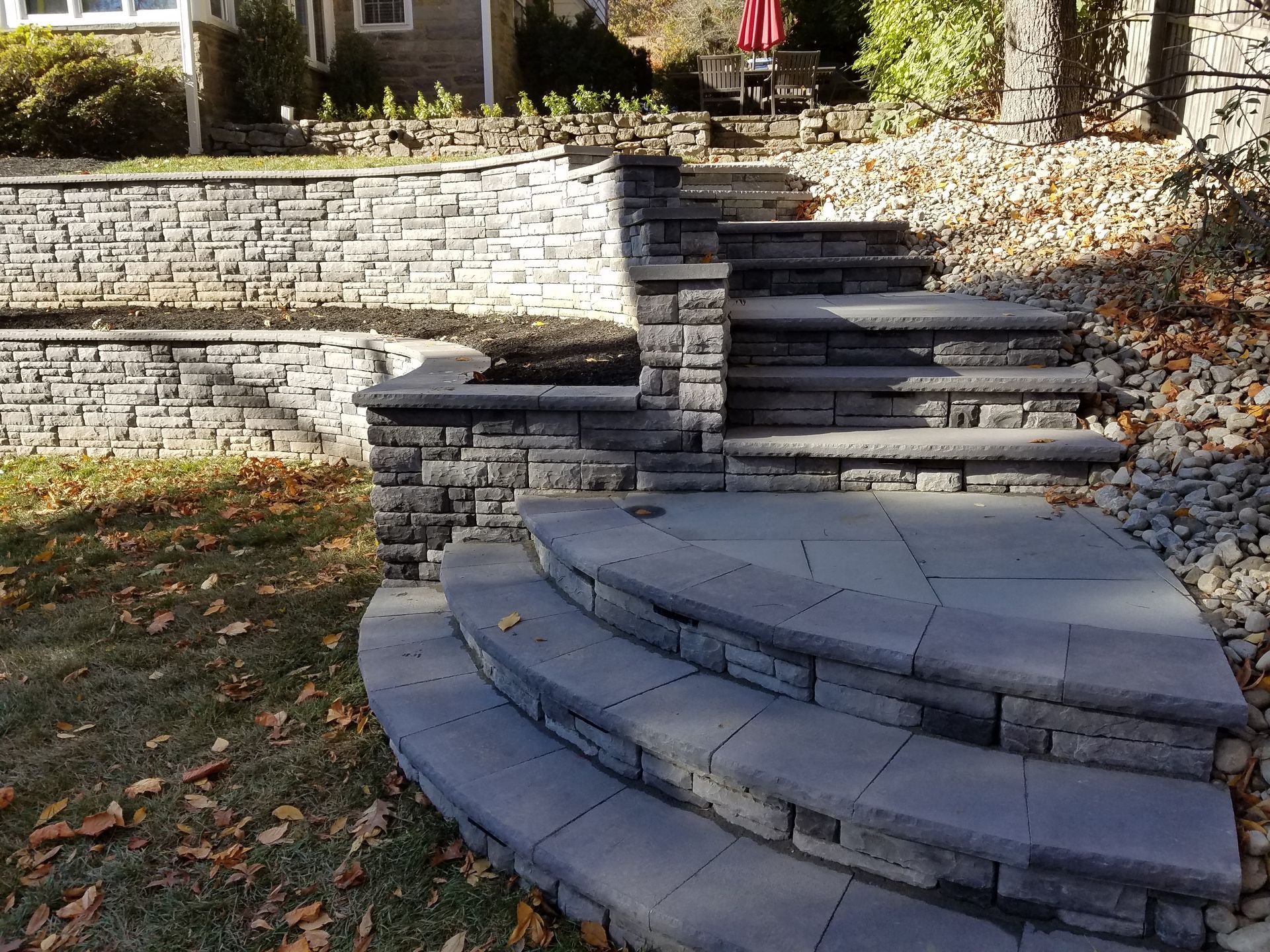 Stone steps and retaining walls leading up a hill to a house.