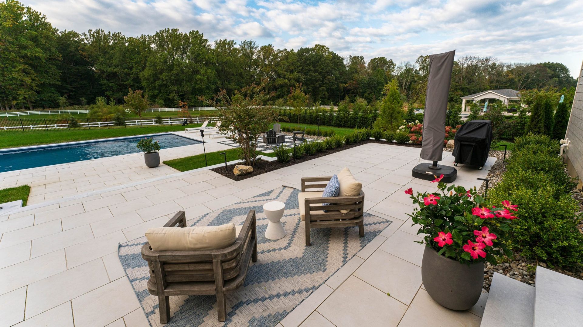 Patio with seating, pool, and garden on a sunny day.