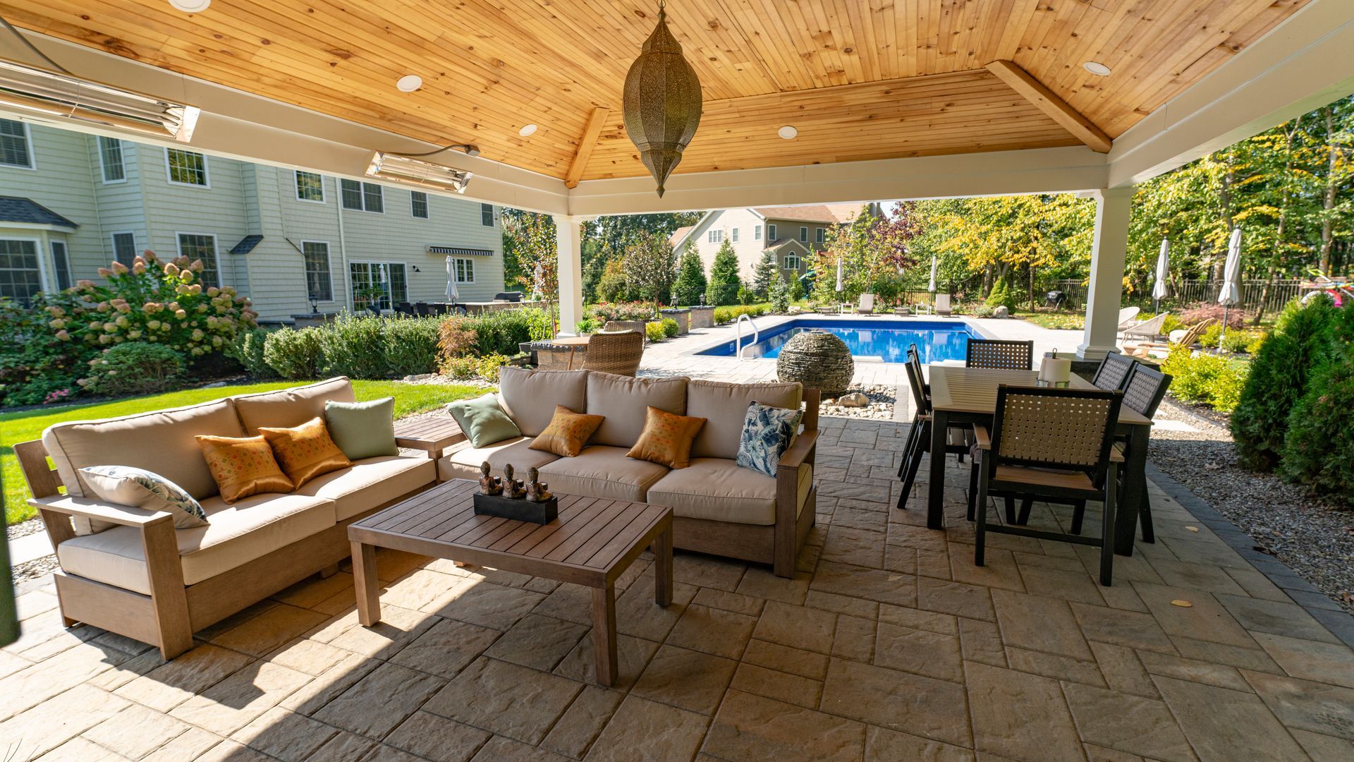 Outdoor patio with seating, wooden ceiling, and a view of a pool.
