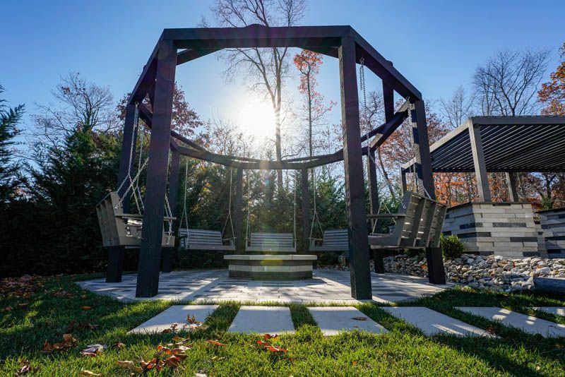 Outdoor swing set with a central fire pit on a sunny day.