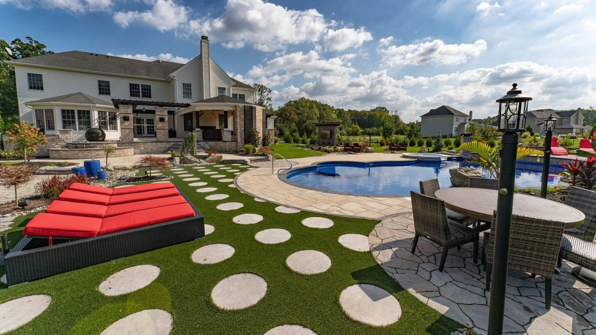A large house with a pool in the backyard. The pool has a cover, and there's patio furniture nearby.