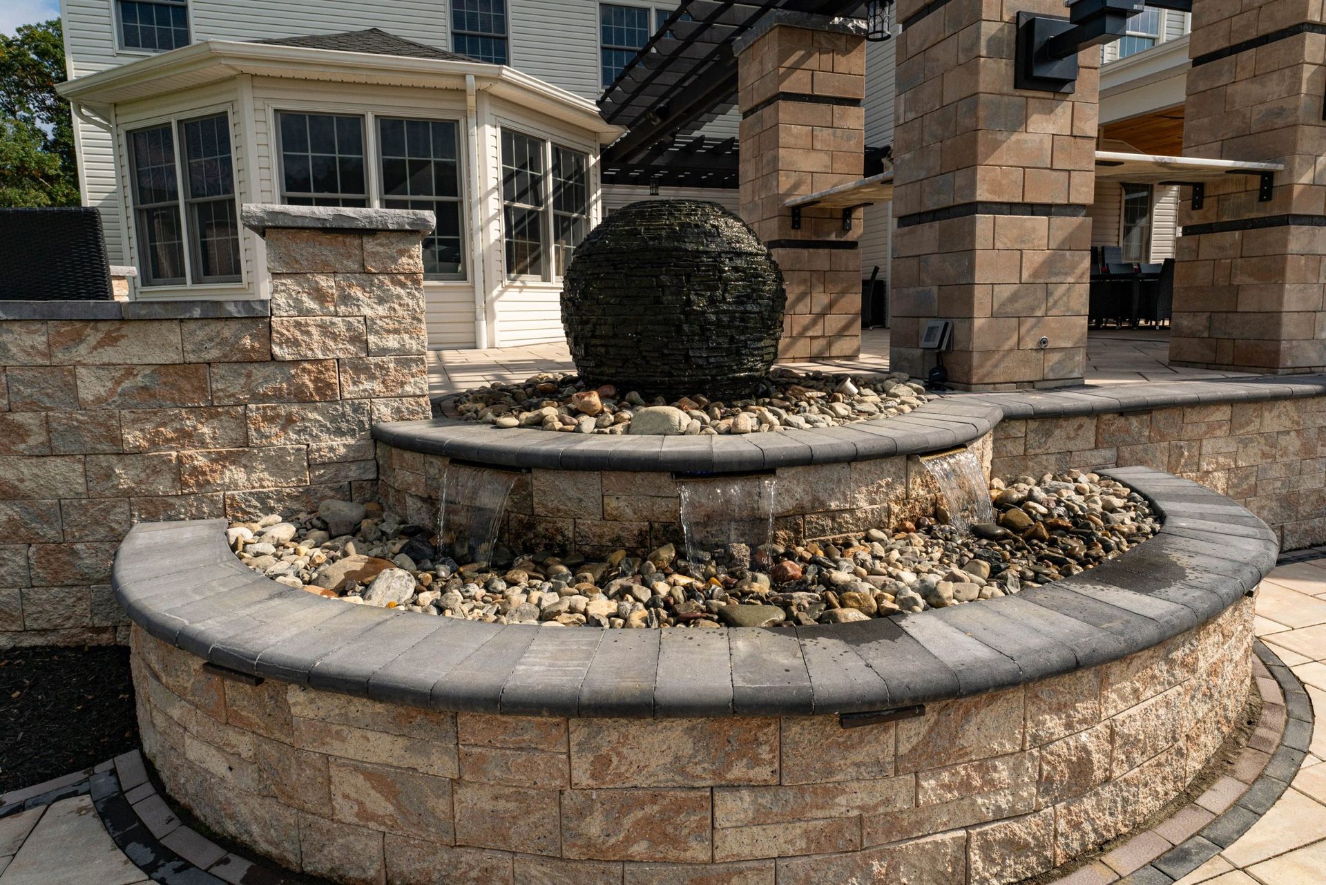 Stone tiered outdoor fountain with a spherical bush.