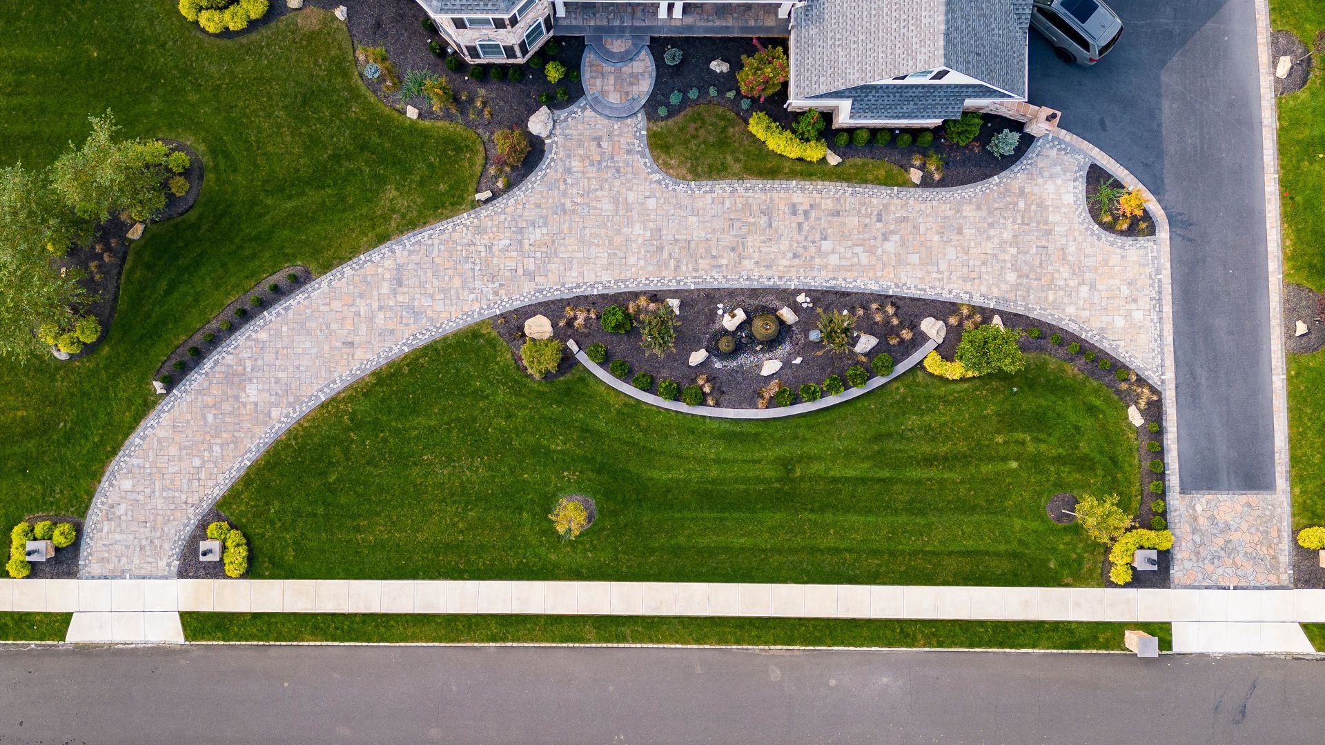Overhead view of a house with a stone driveway and a well-manicured lawn.