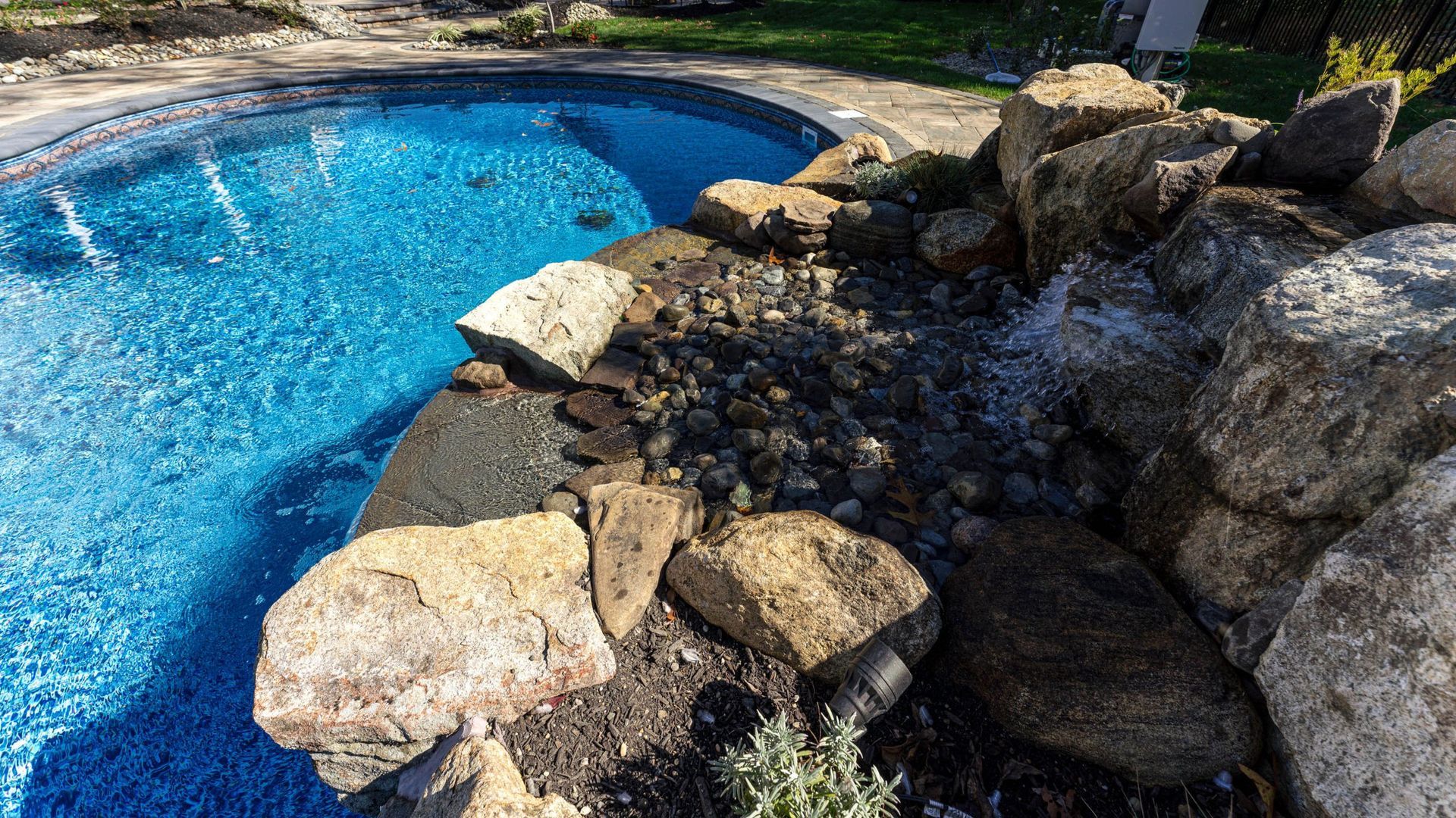 Pool with blue water and a rocky waterfall feature.