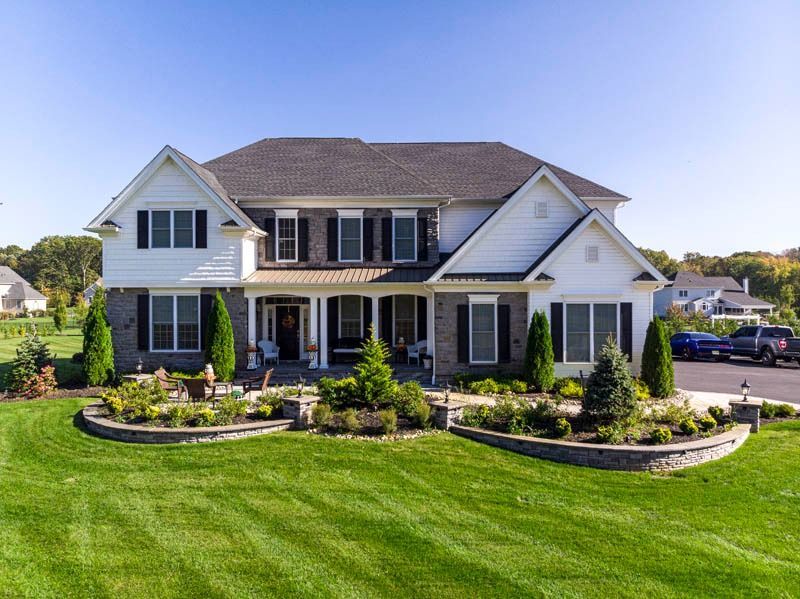 Two-story house with white siding, dark gray roof, and landscaped yard.