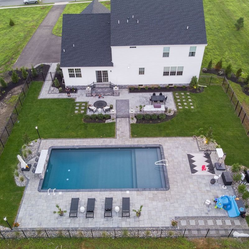 Aerial view of a white house with a pool, patio, and landscaped yard.