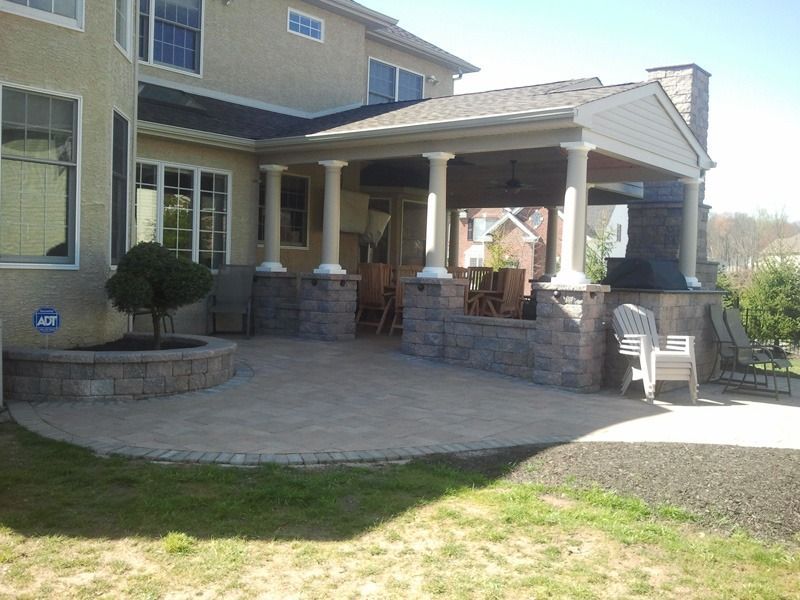 Backyard patio with stone pavers, seating area, and covered porch with pillars.