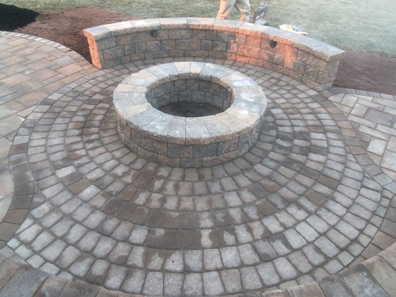 Circular brick patio with fire pit and curved seating wall.