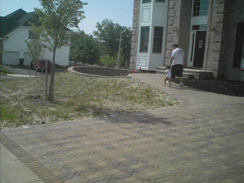 Person and child walking on a brick pathway toward a house with a large entryway.