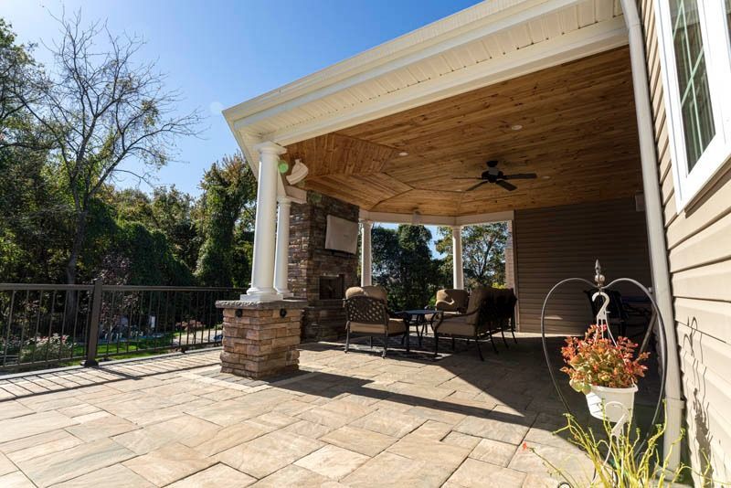 Outdoor patio with stone pavers, seating, and a covered ceiling.
