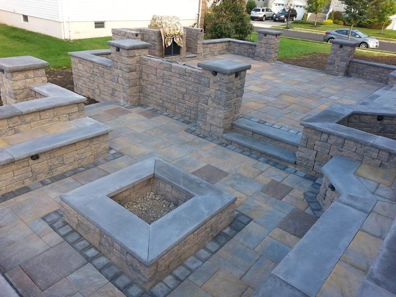 Outdoor patio with stone fire pit, seating walls, and multi-tone pavers.