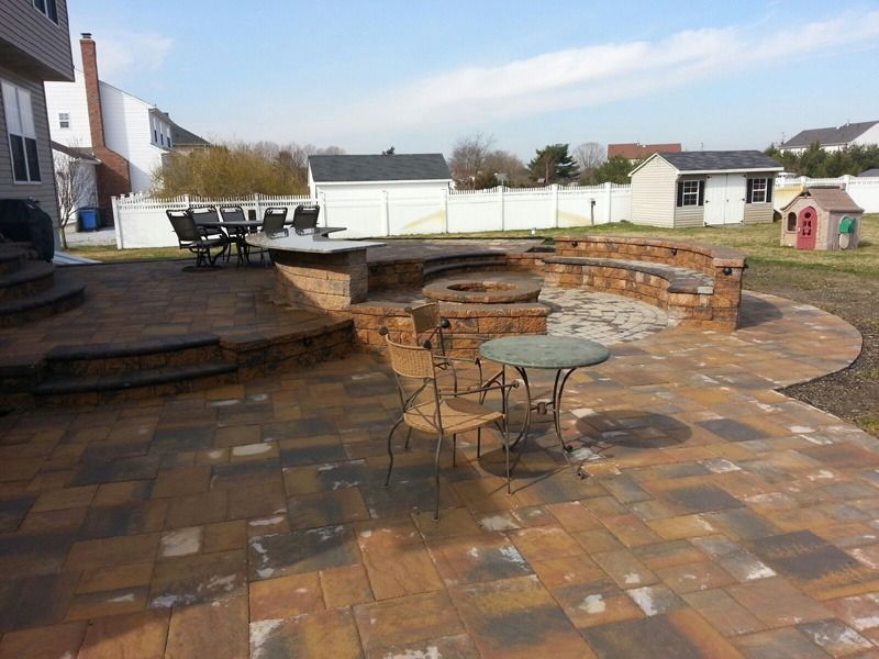 Patio with brick pavers, built-in seating around a fire pit, and dining table.