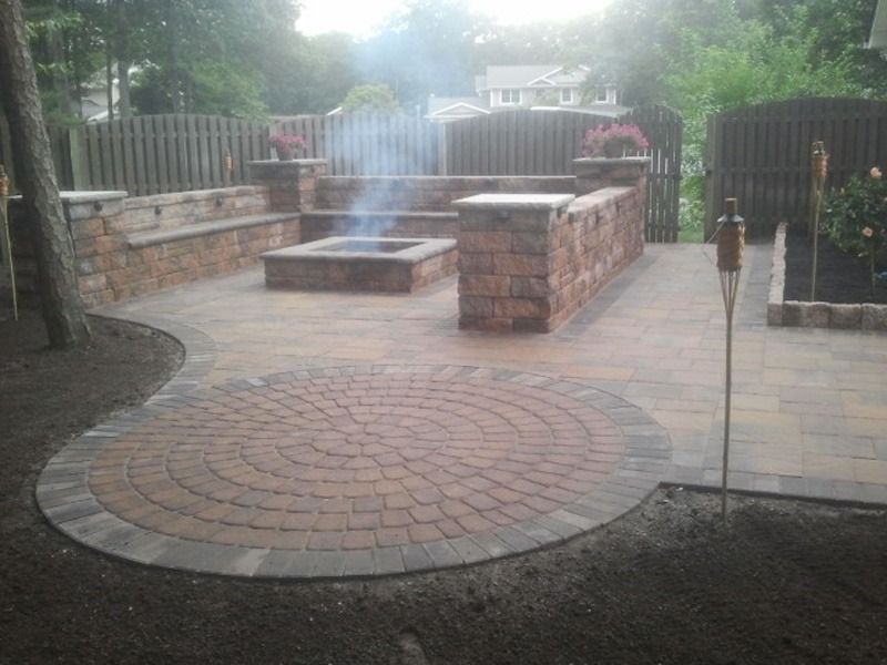 Patio with brick fire pit, seating, and circular brick area.