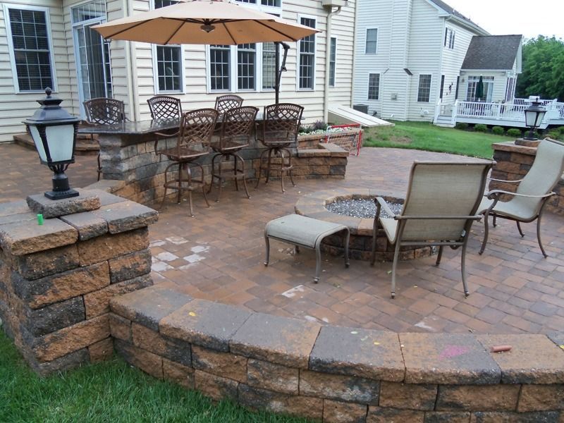 Patio with brick pavers, built-in bar with stools, fire pit, and outdoor seating.