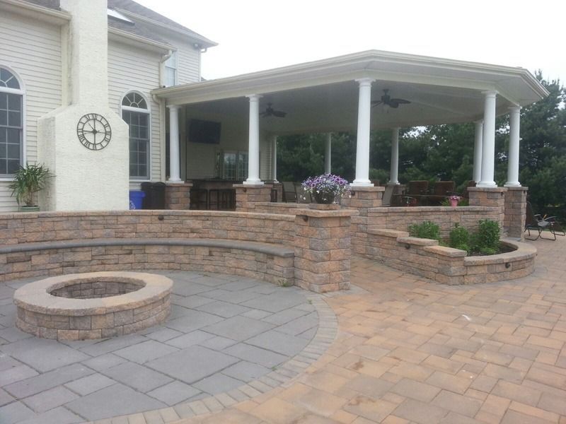 Outdoor patio with a stone fire pit, seating wall, and covered gazebo.