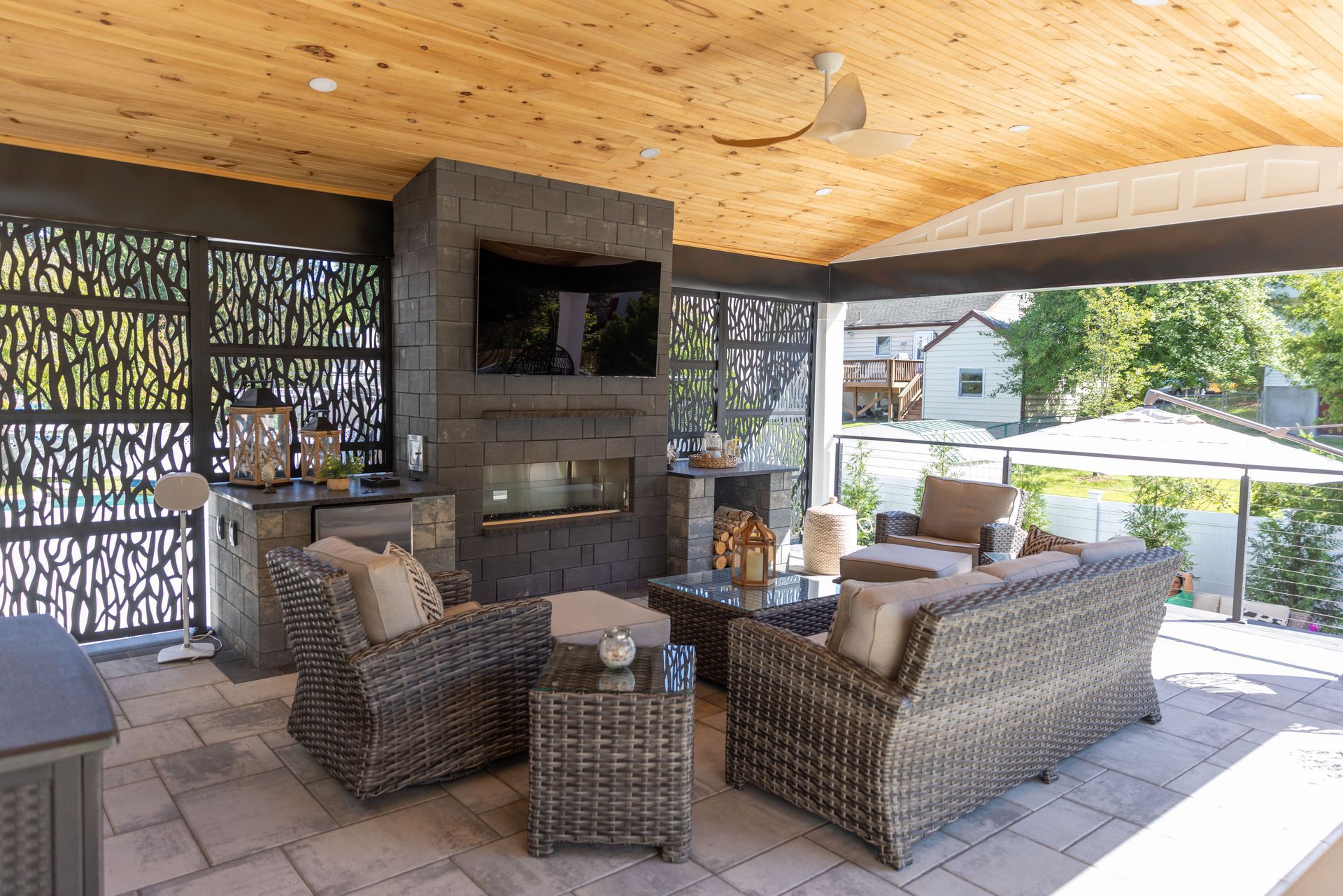 Outdoor patio with wicker furniture, fireplace, TV, and decorative screens.