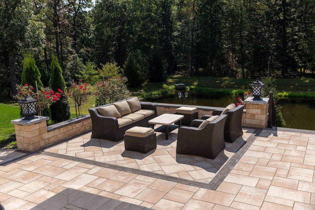 Patio with outdoor seating overlooking a pond, surrounded by trees.