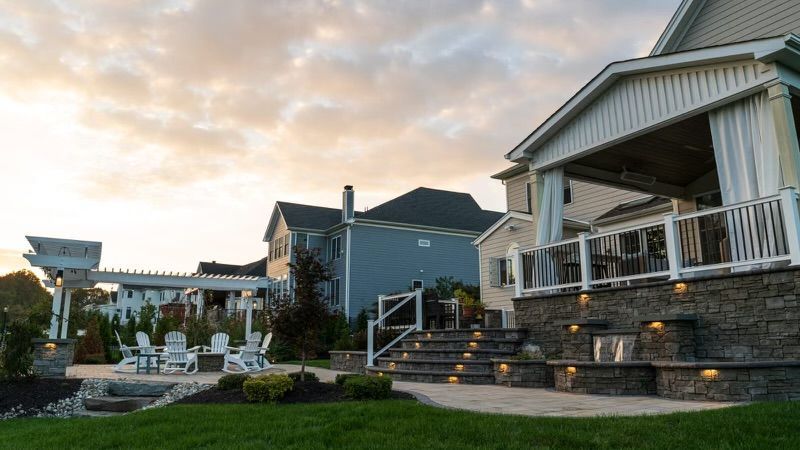 Backyard patio with stone, seating, and a covered porch. Houses in background.