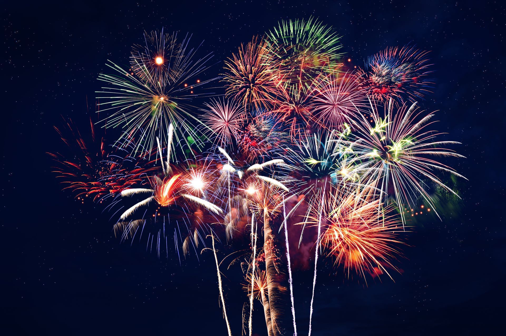 Fireworks in various colors burst against a dark night sky.