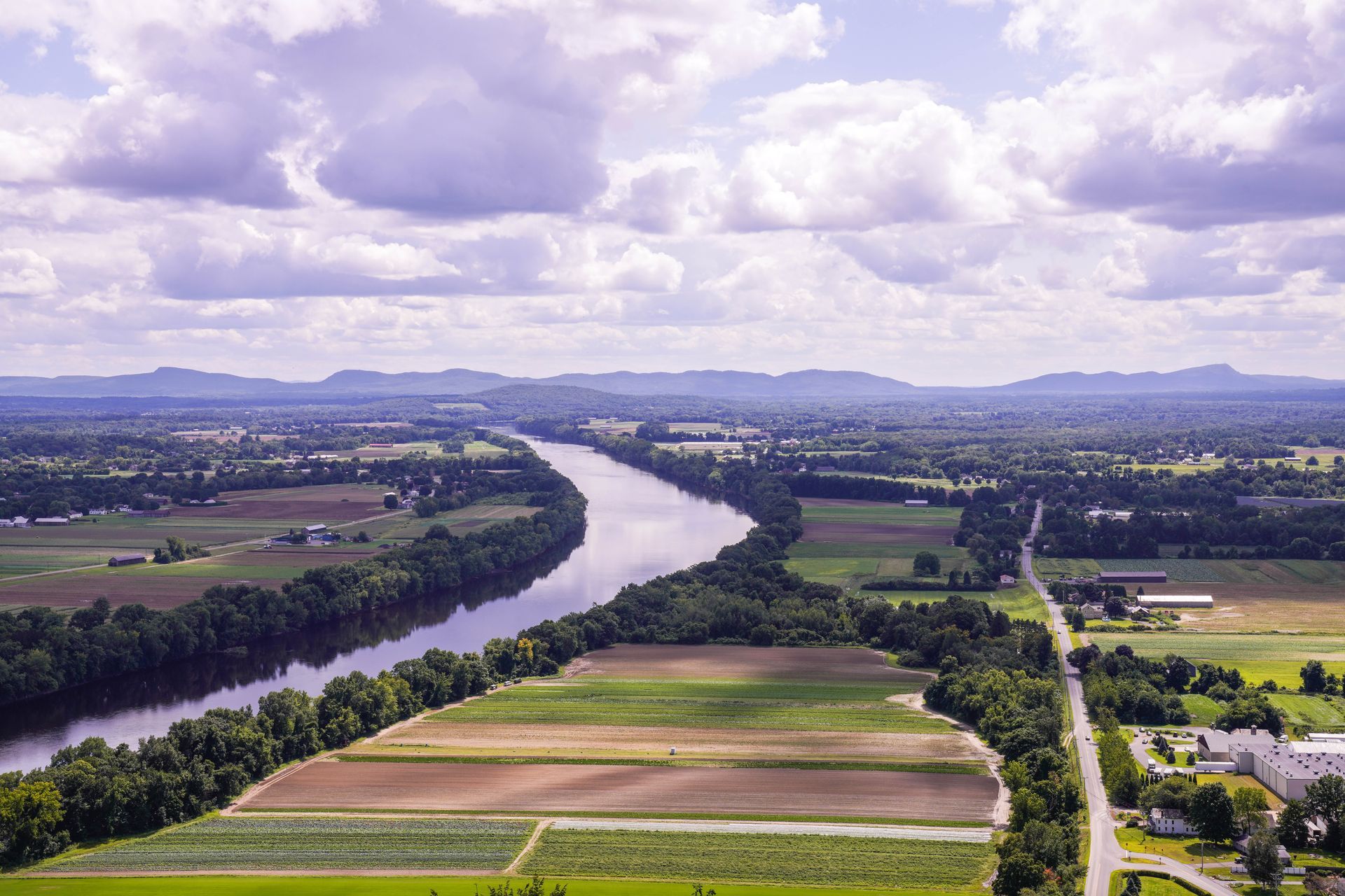 An aerial view of a river surrounded by fields and mountains.