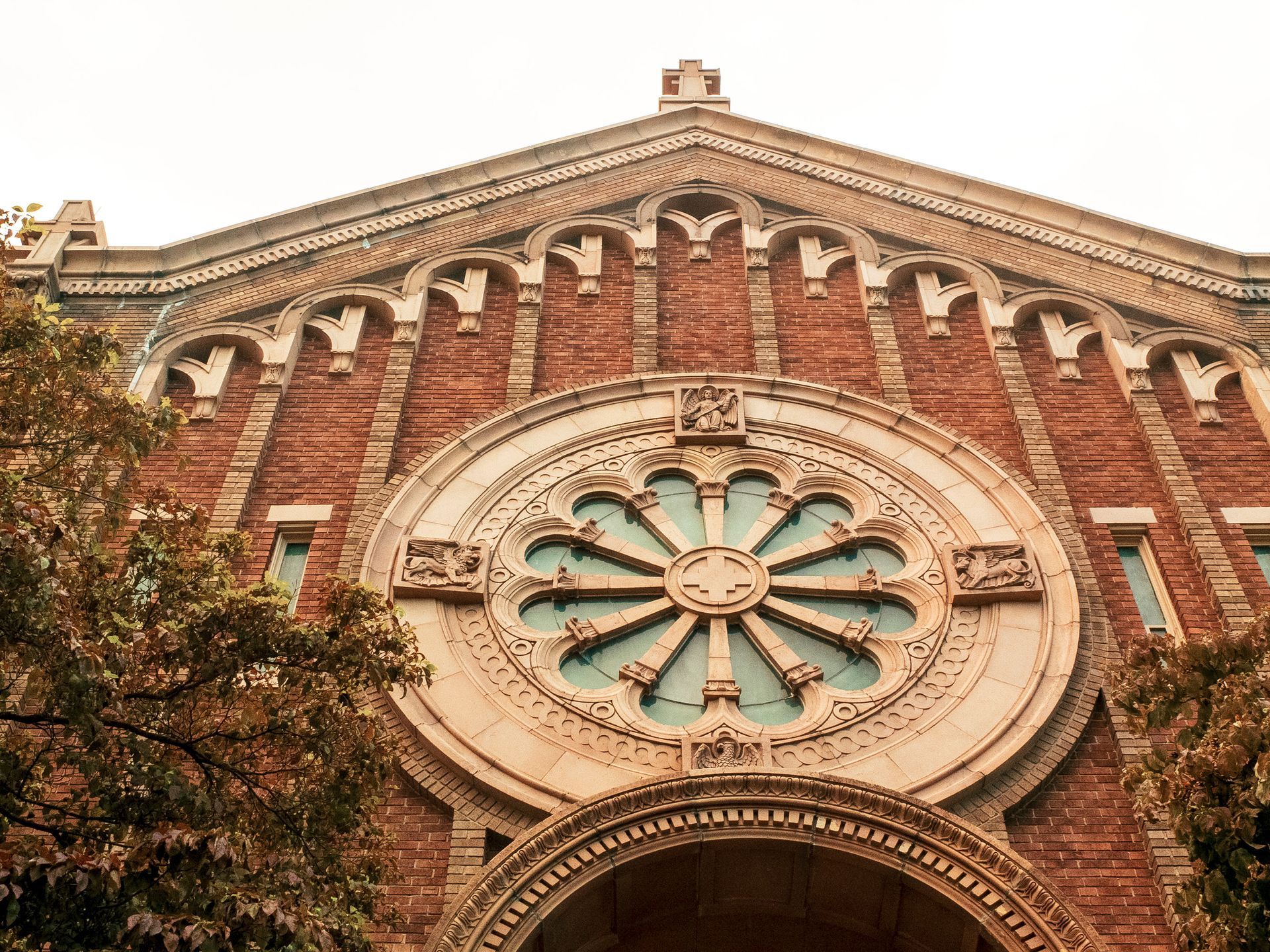 Red brick church facade with rose window and arched entrance.