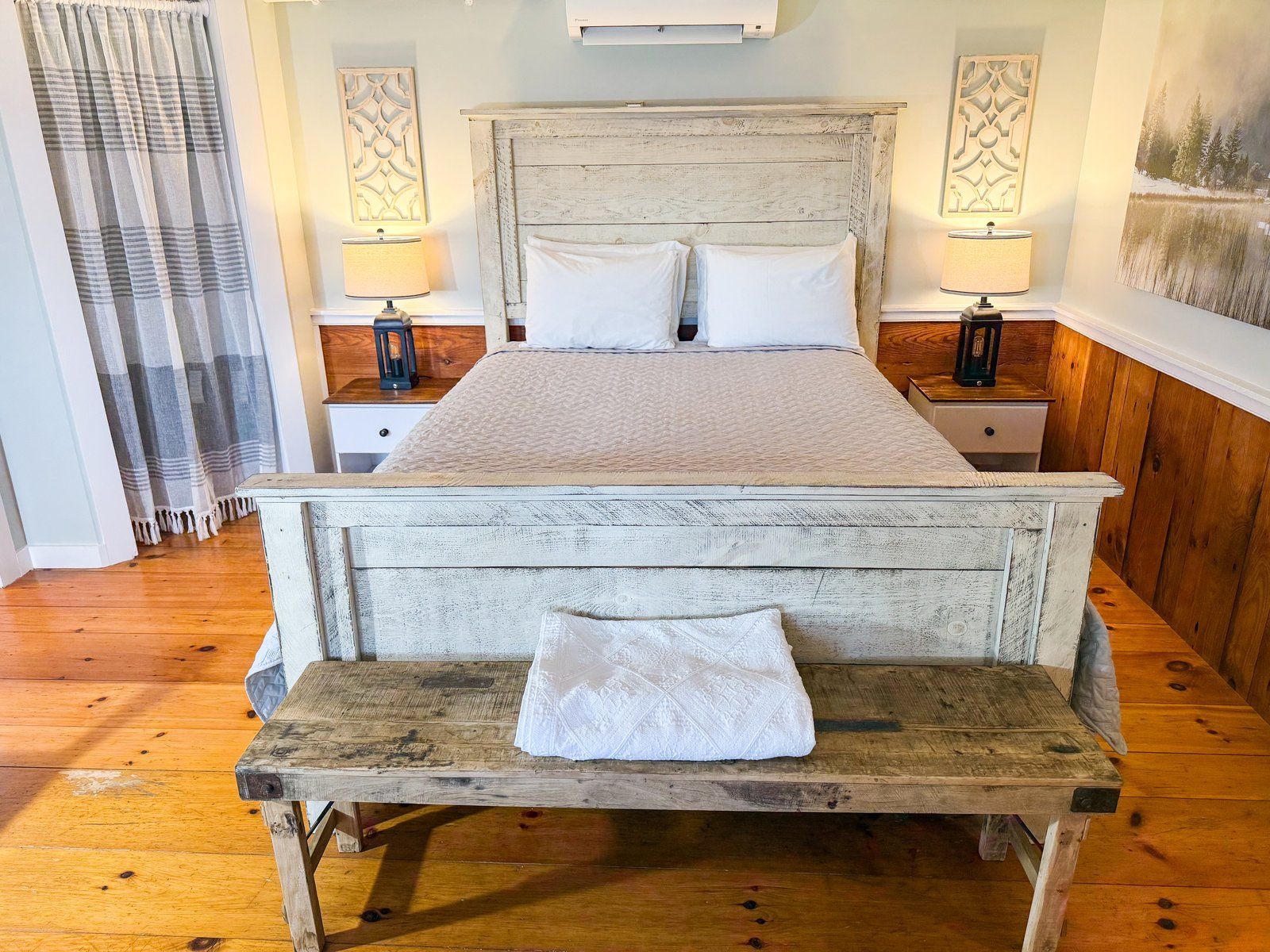 A bedroom with a king size bed and a wooden bench.