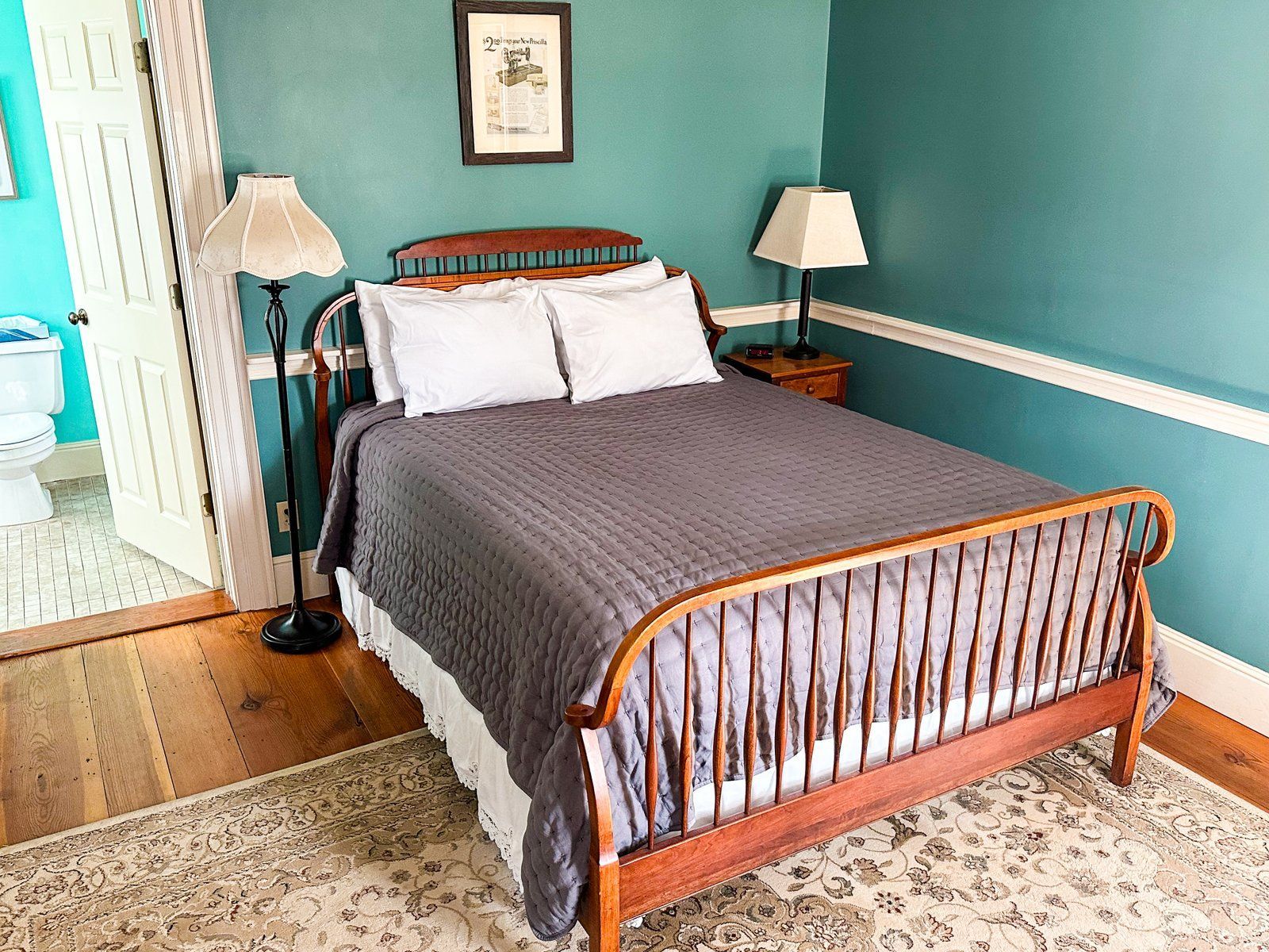 A bedroom with a bed , two lamps , and a rug.