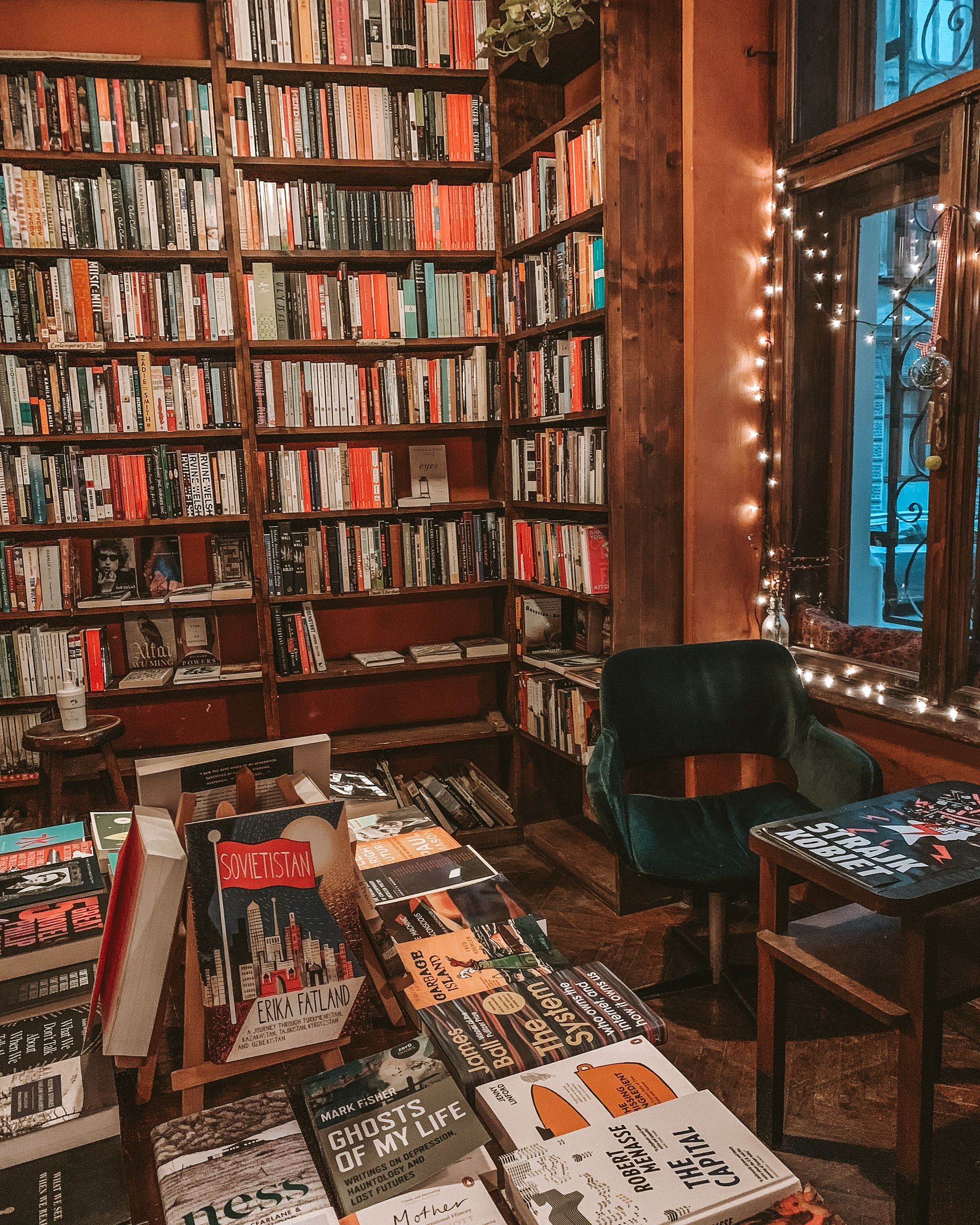 Cozy bookstore interior with overflowing bookshelves, a reading chair, and fairy lights.