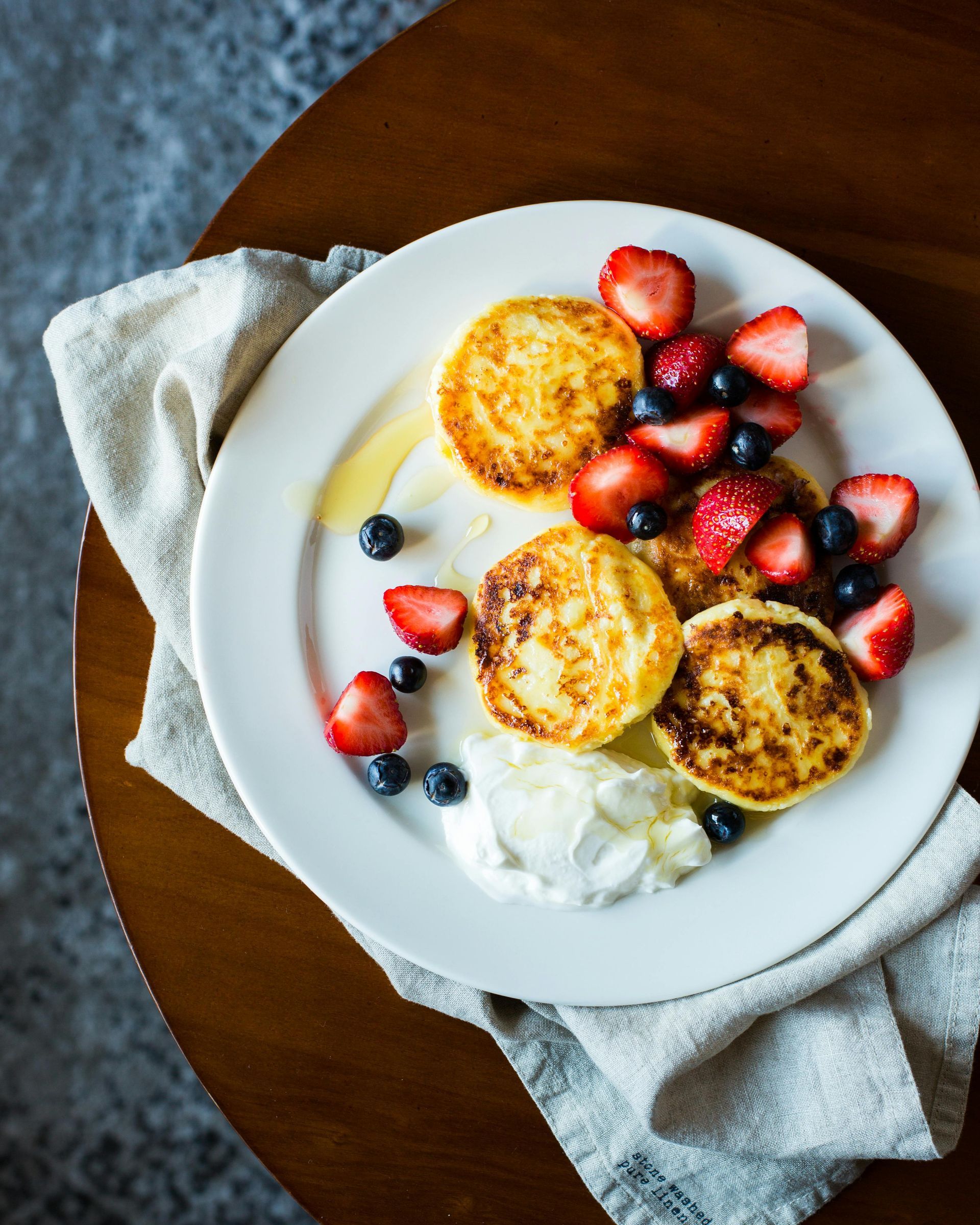 A white plate topped with pancakes strawberries and blueberries