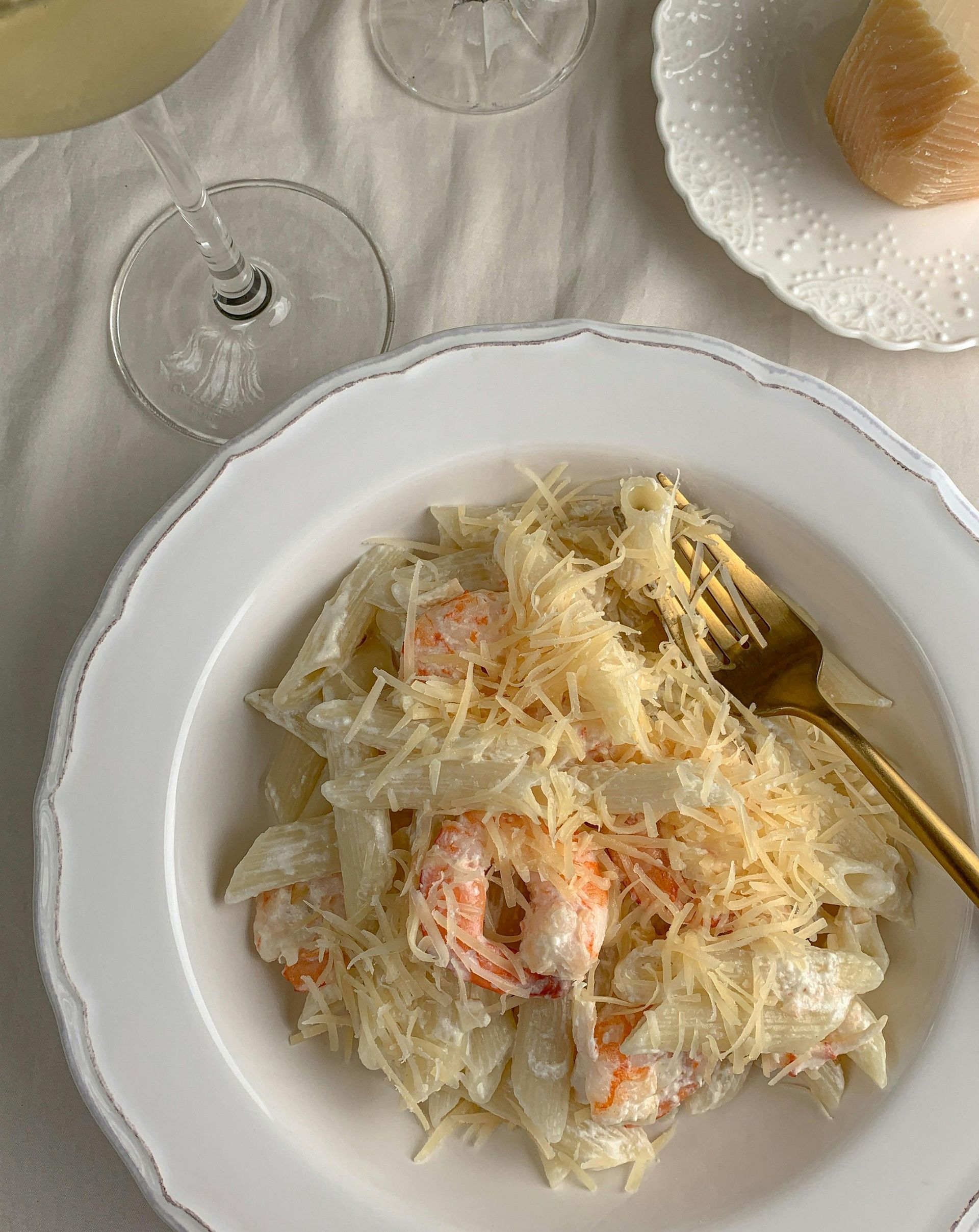 A plate of food with a fork and a glass of wine on a table.