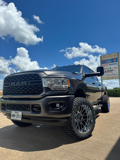 A black ram truck is parked in a parking lot next to a sign.