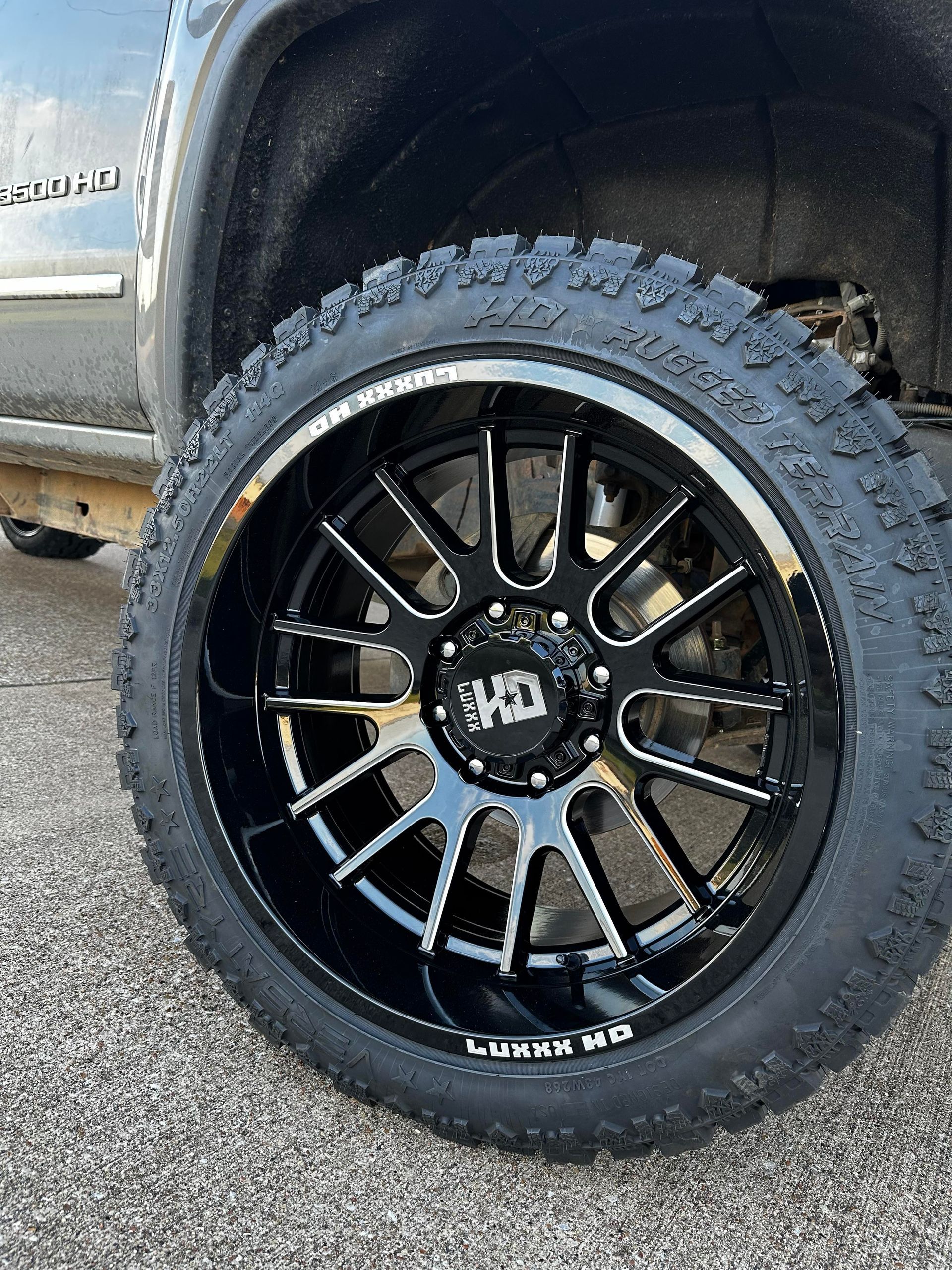 Black truck wheel with a shiny black rim and off-road tire.