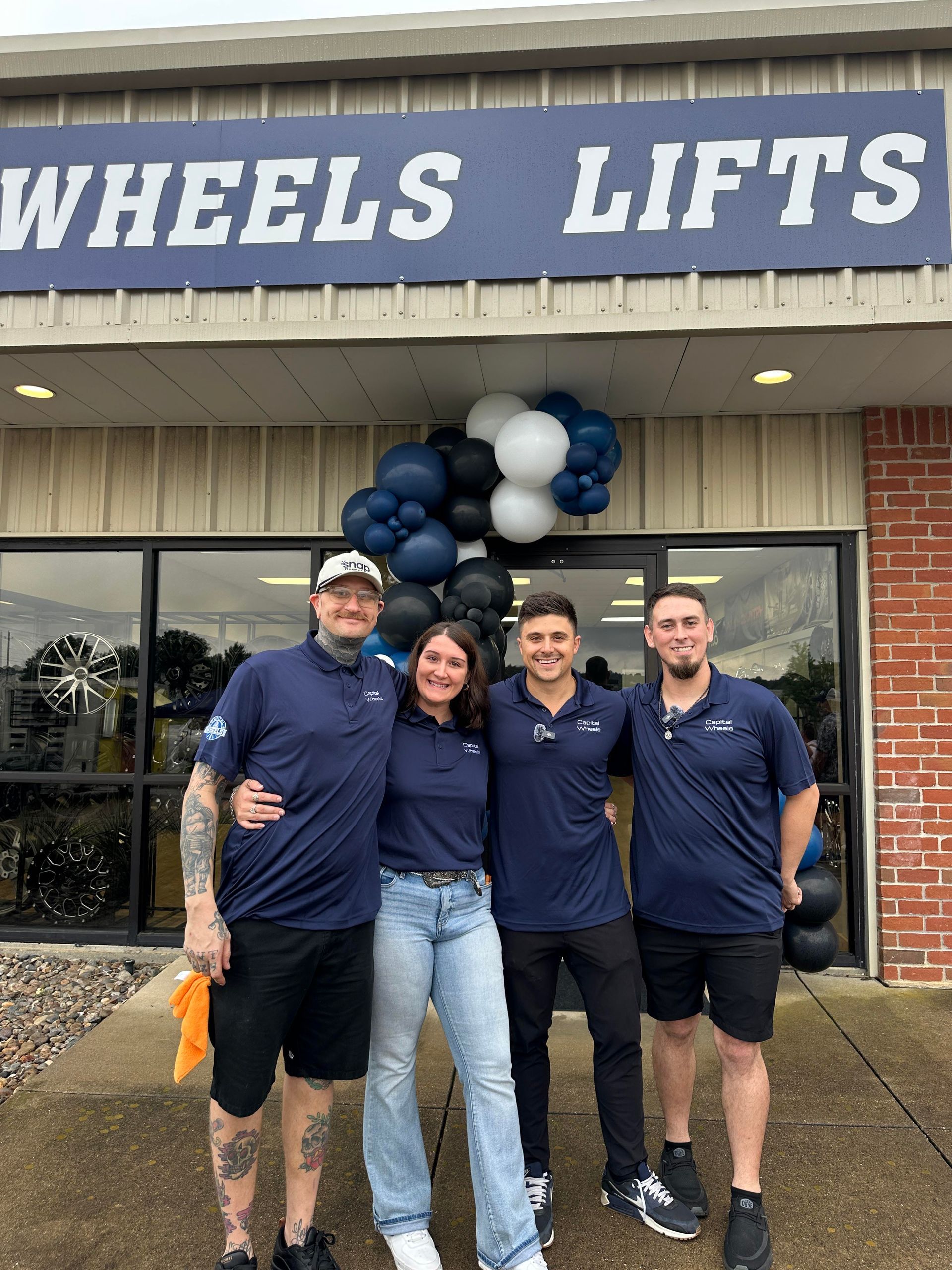 Four people pose in front of a business with