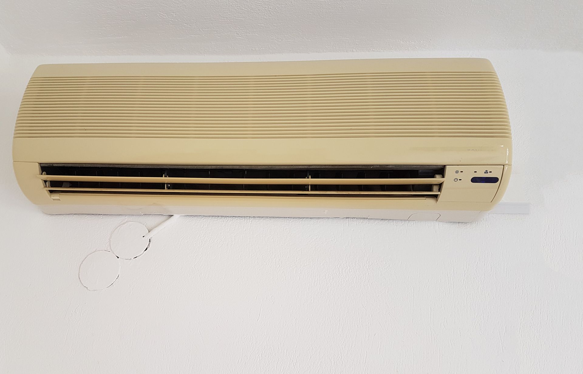 Image of an old wall-mounted air conditioner with manual control panel.