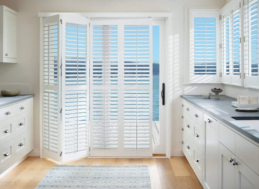 Kitchen with a sliding glass door with Hunter Douglas Palm Beach Shutters