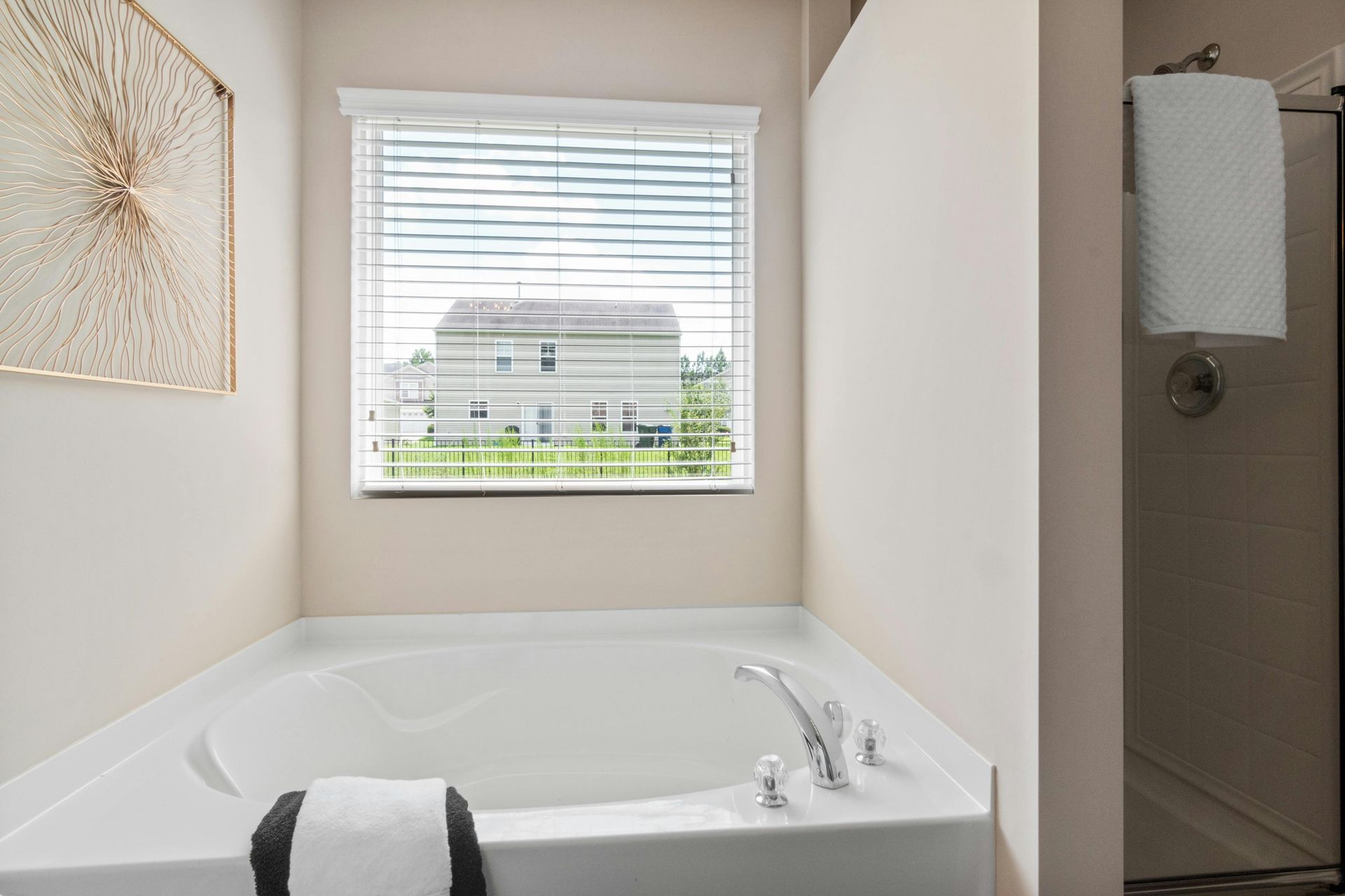 Bathroom blinds covering a window above a white soaking tub in a modern bathroom, i