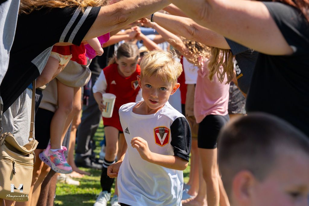 young soccer player running through a tunnel created by the raised arms of adults
