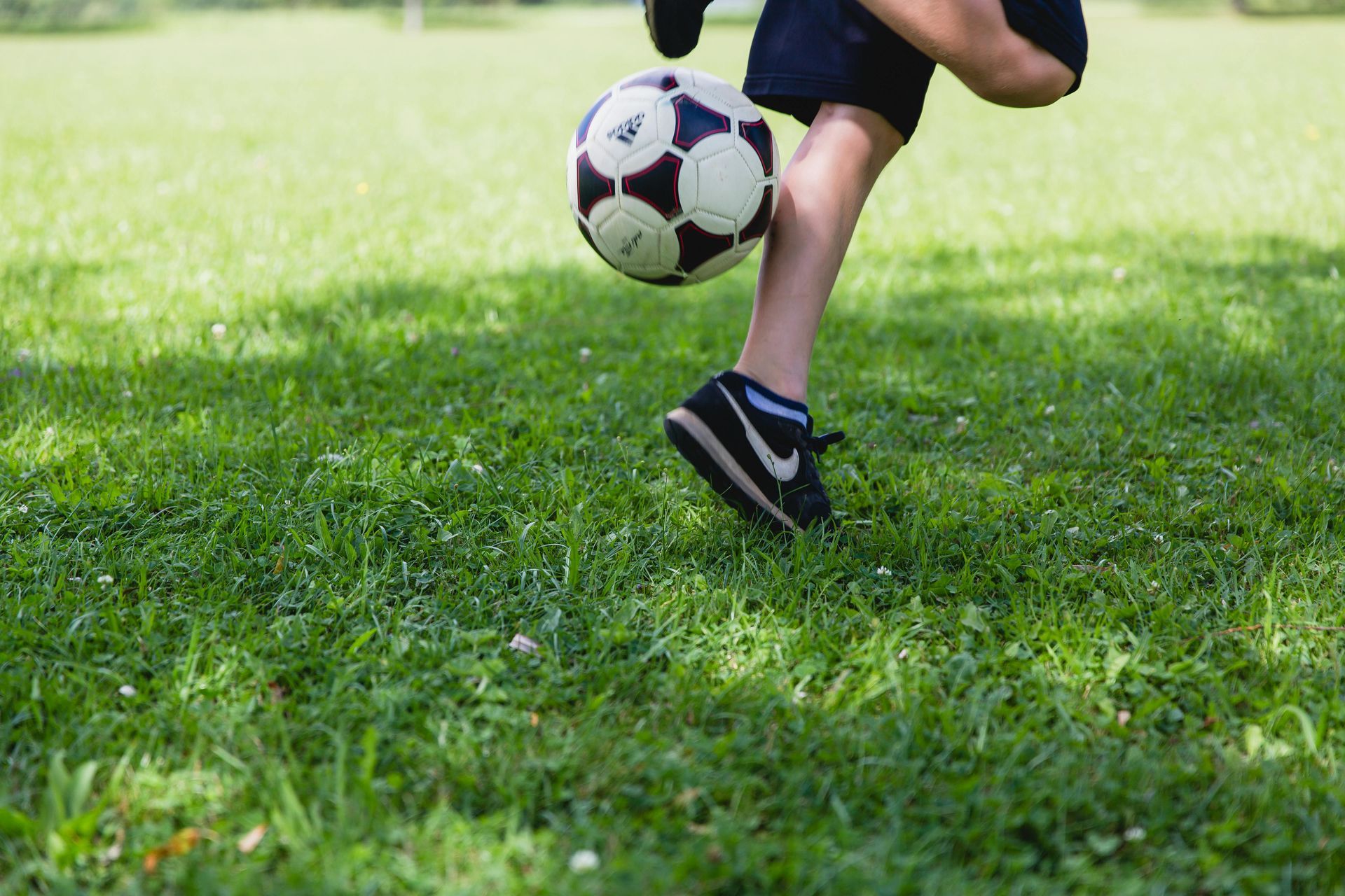 legs of a soccer player kicking a soccer ball behind him