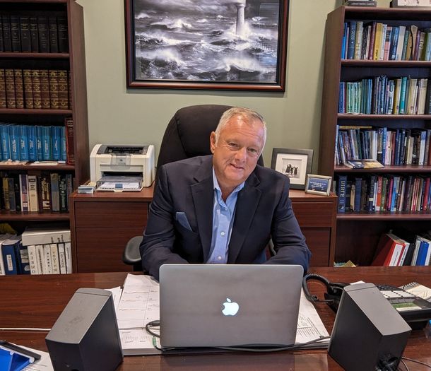 David Mahler Addiction Recovery Coach sitting at a desk with an apple laptop