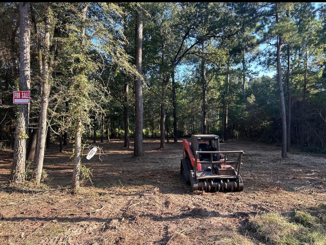 A small excavator in a cleared wooded area, a 
