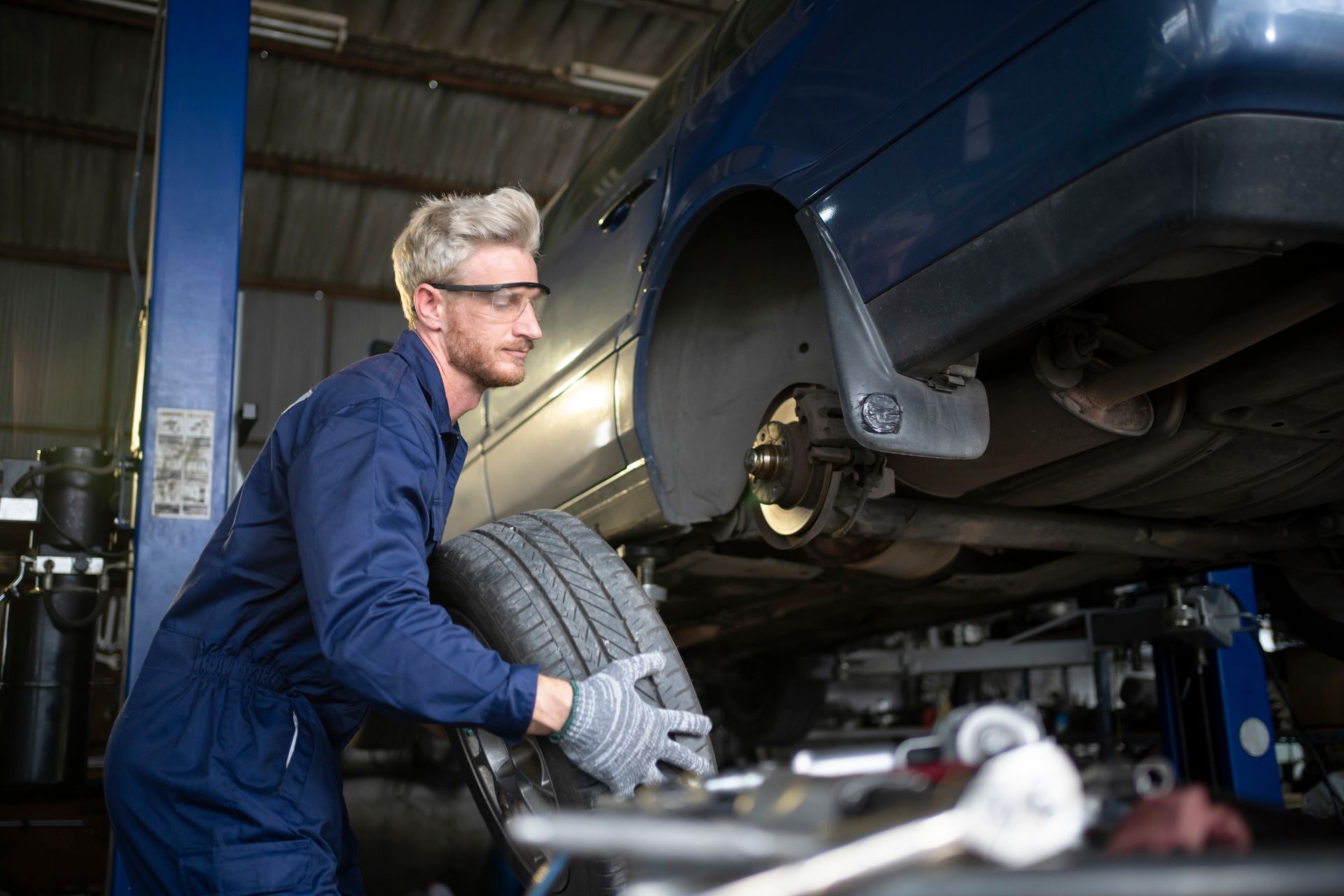 Full length of young engineer adjusting car tire. Full length of young engineer adjusting car tire.