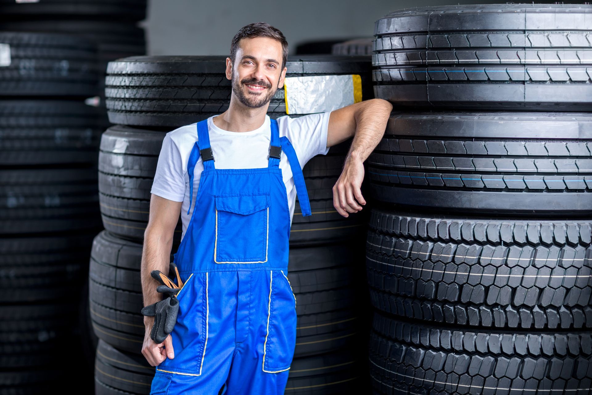 A man in blue overalls next to tires at Blue Ridge Tire Center in Roanoke, VA.