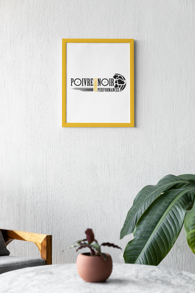 Œuvre encadrée jaune sur un mur blanc. Ci-dessous, une plante sur une table à côté d'un canapé gris.