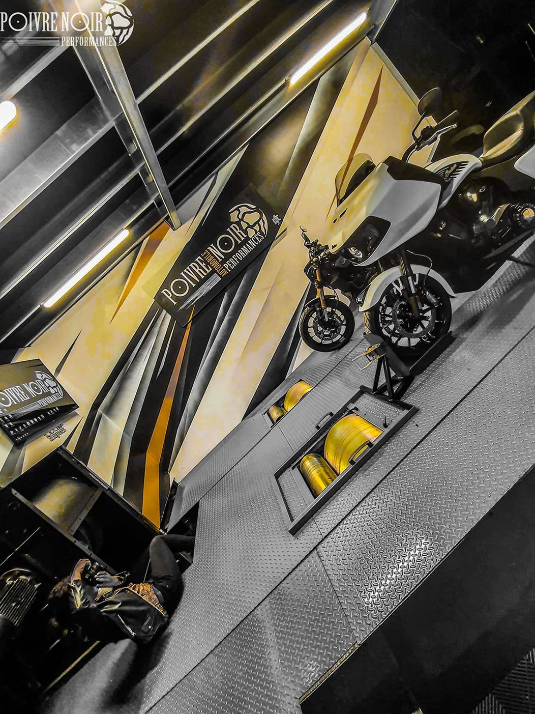 Moto exposée près d'un logo jaune et noir sur le mur.