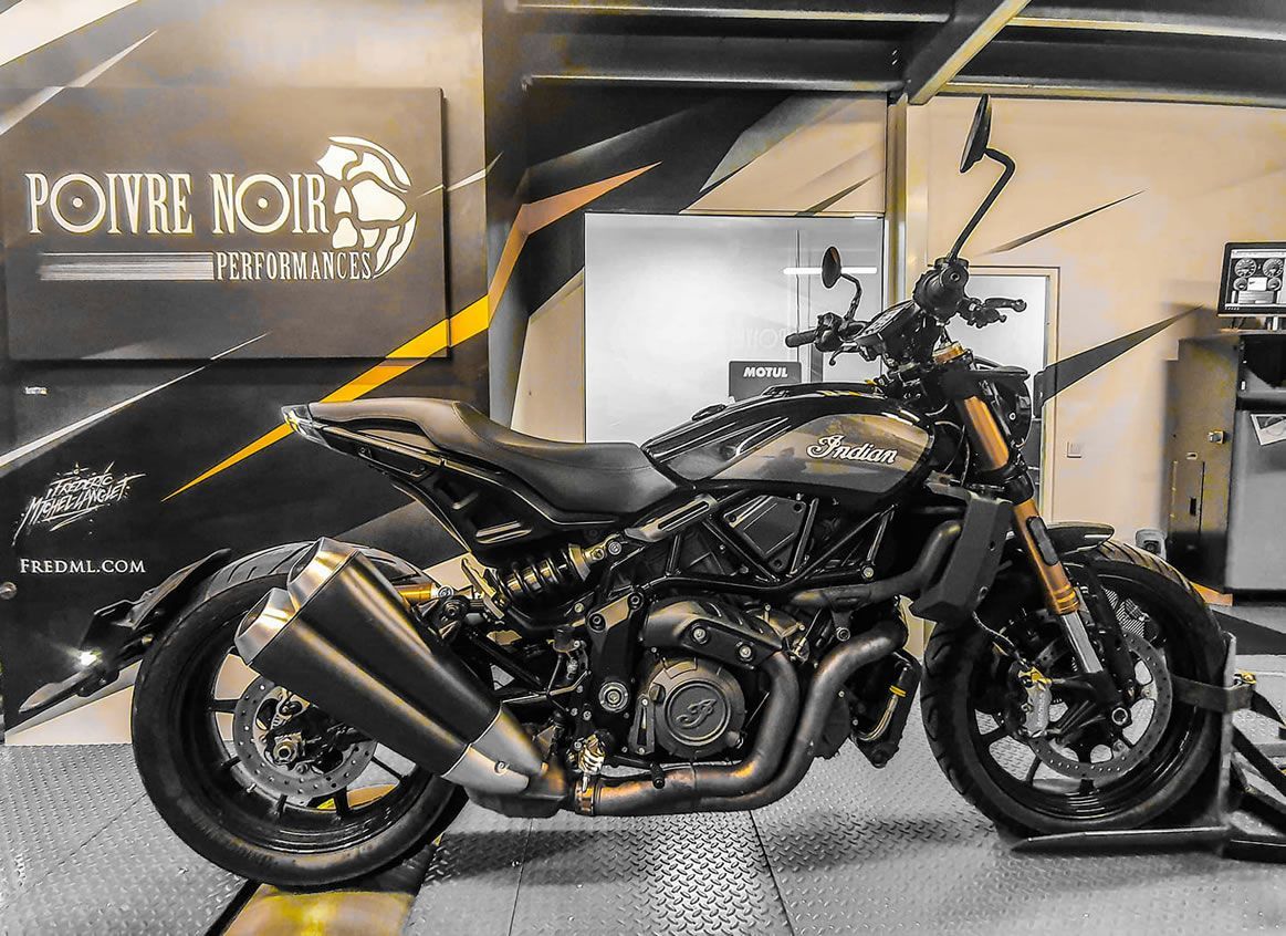 Moto indienne personnalisée sombre à l'intérieur d'un magasin avec peinture personnalisée et double échappement.